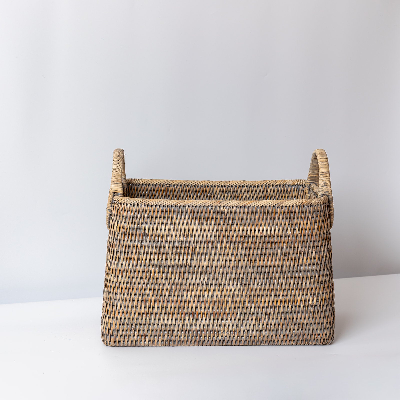Woven basket with handles on a white surface and light gray background