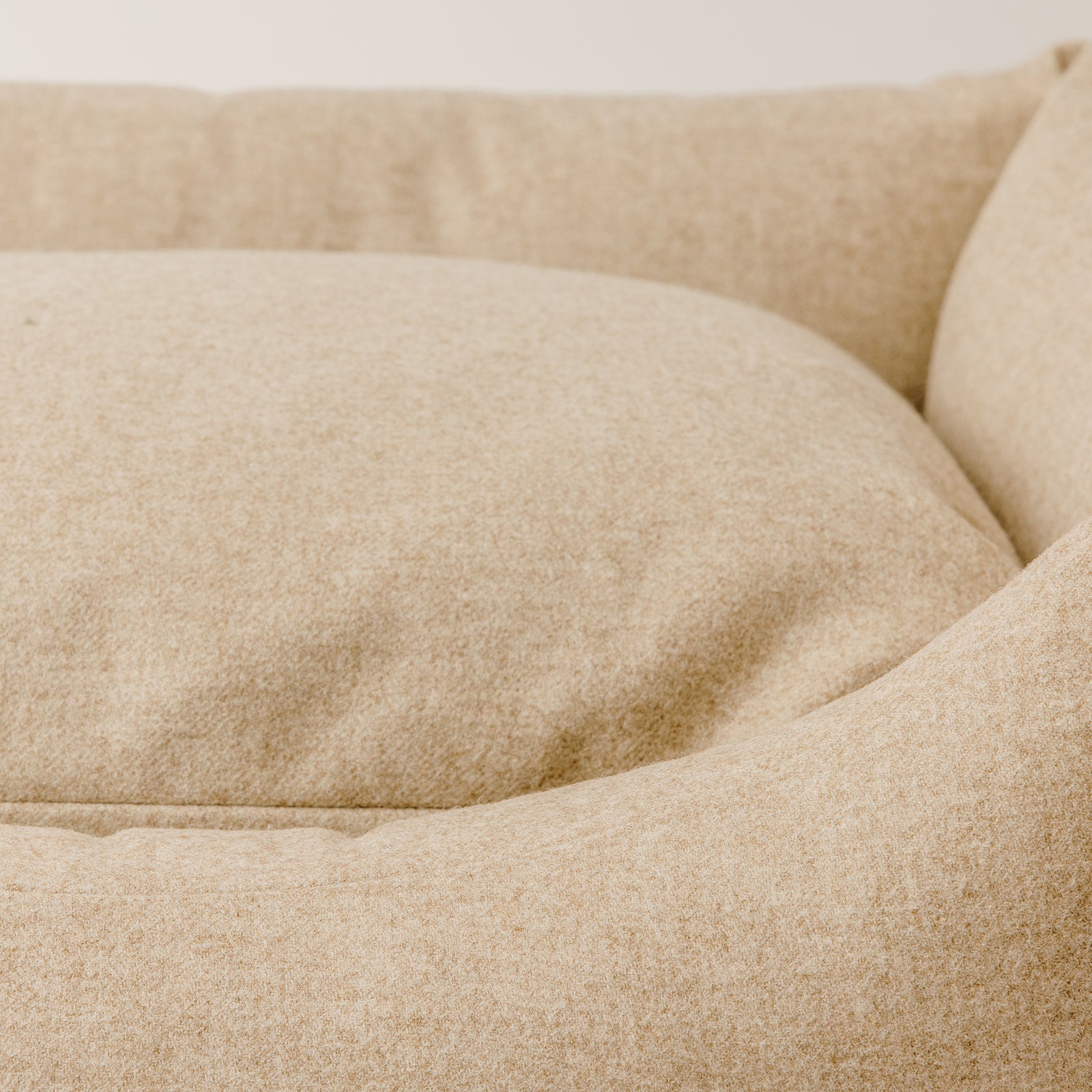 A close up image of a luxury wool dog bed in a light beige fabric 