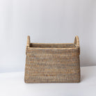 Woven basket with handles on a white surface and light gray background