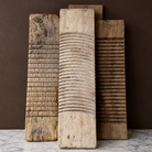 Three rustic wooden washboards of varying sizes and textures, standing upright on a white marble surface against a dark brown background.