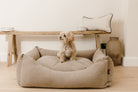 Dog sitting on a luxury linen cotton dog bed in a neutral home setting